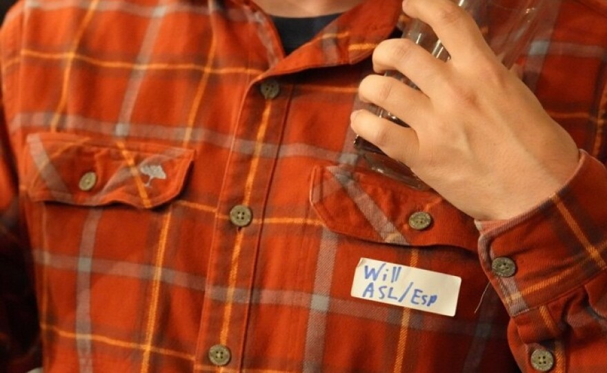 Language Exchange night participant, Will Cuddy, holds his drink while mingling 