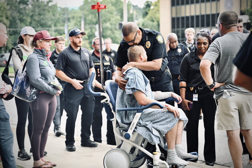 An officer comforts Columbia Police Department officer David Dymock, who was injured in a shooting on Aug. 29, 2026, in Columbia that killed his colleague, officer Christopher DeLong.
