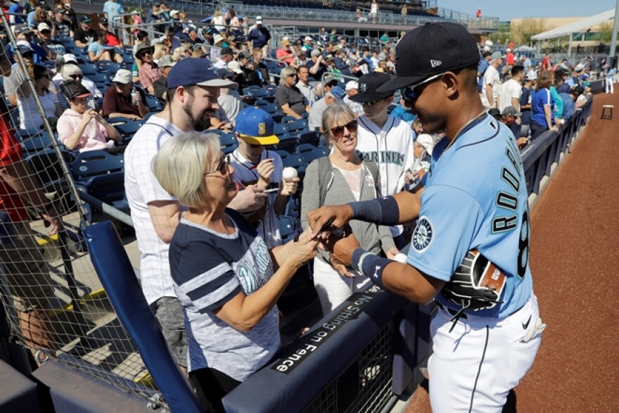 Seattle Mariners rookie phenom Julio Rodriguez signs autographs before a spring training baseball game in Peoria, Ariz.