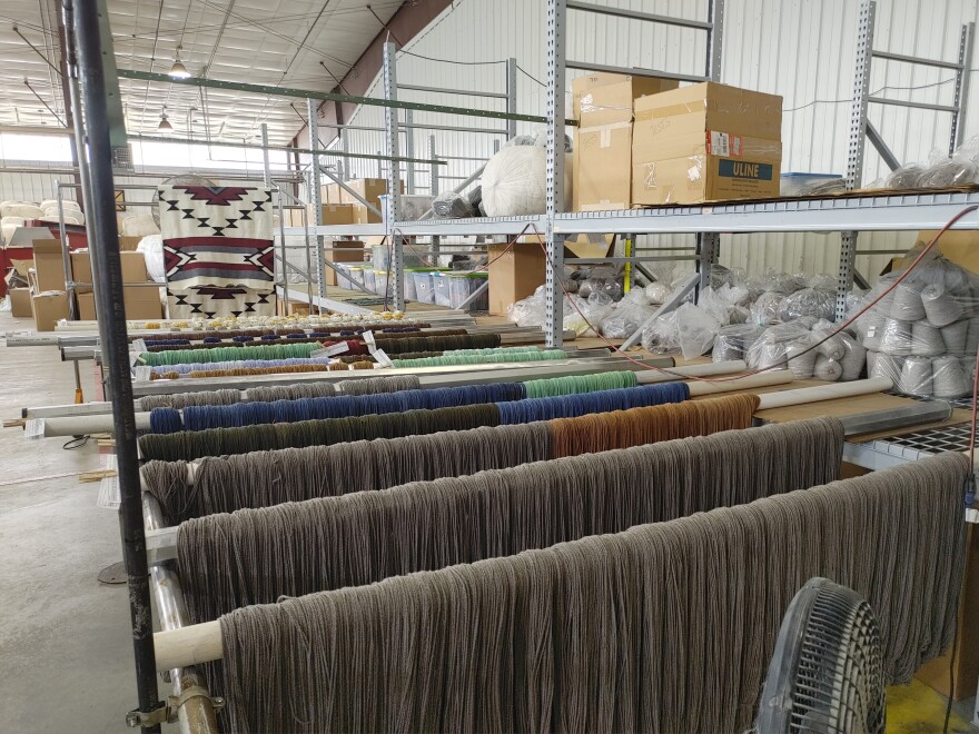 Dyed wool yarn is hung over poles to dry.