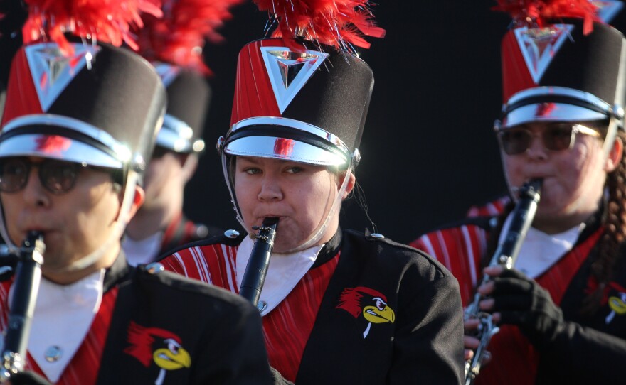 Fans and marching band members greet ISU football players and coaches