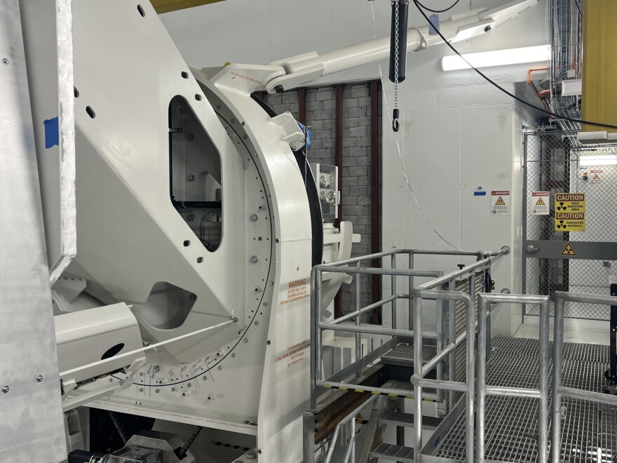 The massive structure that houses the proton beam. The ceiling of this room is removable, in case the beam ever needs craned out and replaced. A mechanical looking room with radiation warning signs houses a massive, cylindrical container, the housing for the proton beam.