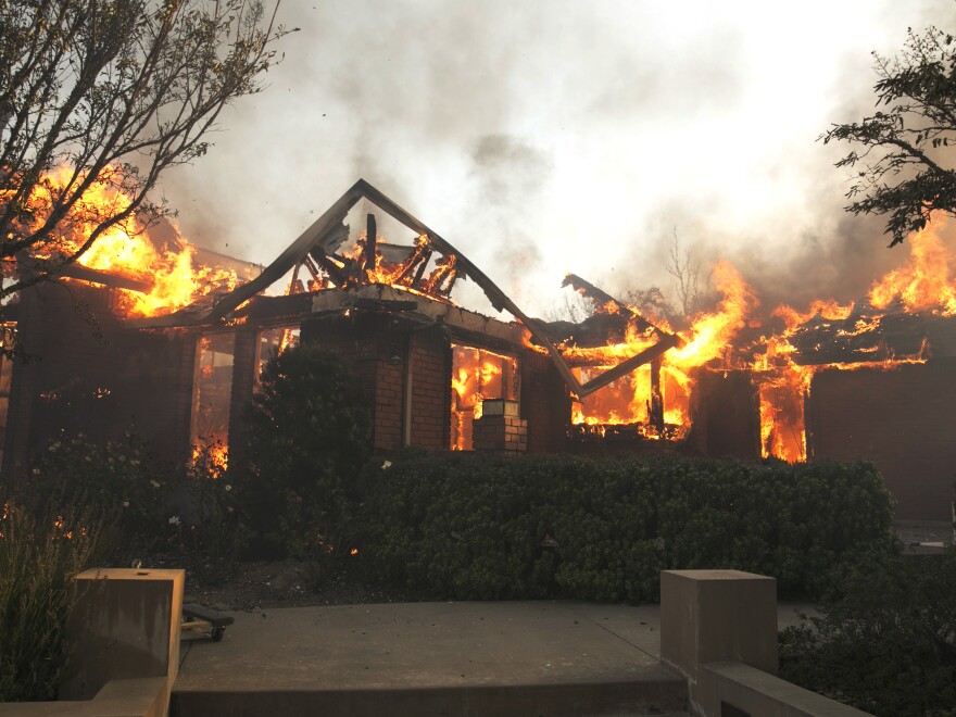 Flames from a wildfire consume a home Monday, east of Napa, Calif.