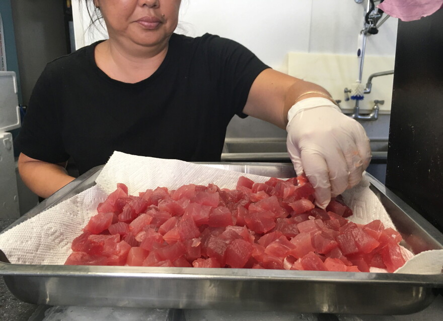 FILE - This Tuesday, April 16, 2019 photo shows Michele Miyanaga preparing cubes of raw ahi, or tuna, at Aloha Poke Shop, a store in Honolulu that received a letter from Chicago-based Aloha Poke Co. saying the Illinois company had trademarked "Aloha Poke" and the Hawaiʻi company would need to change its name. (AP Photo/Audrey McAvoy)