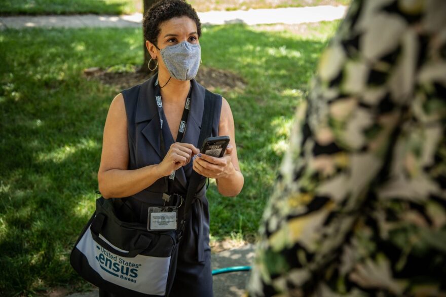 A masked US Census taker takes notes in the field