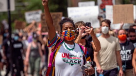 A woman holds her fist in the air as she marches during a Black Lives Matter rally calling for racial justice following the murders of George Floyd and Breonna Taylor, Saturday, June 28, 2020, in Cincinnati.