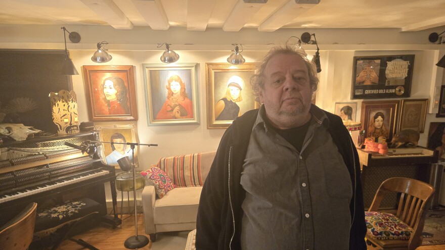 Christopher Colbert stands in front of an eclectically decorated wall in National Freedom Studio