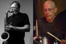 Two guys wearing black t-shirts. The one on the left playing a saxophone and the one on the right playing drums.