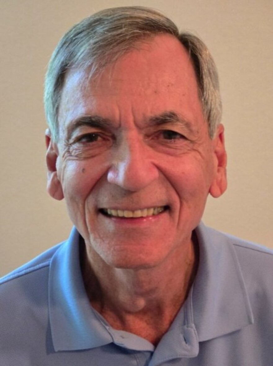 Close-up of an older man with gray hair smiling into the camera