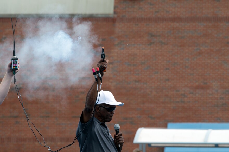 The starter fires the starting pistol to begin a race at the 2023 Pepsi Florida Relay at the James G. Pressly Stadium in Gainesville, Fla., on Apr. 1, 2023. The pistol shot smoke into the air after waiting for the athletes to settle into position. (Augustus Hoff/WUFT News)