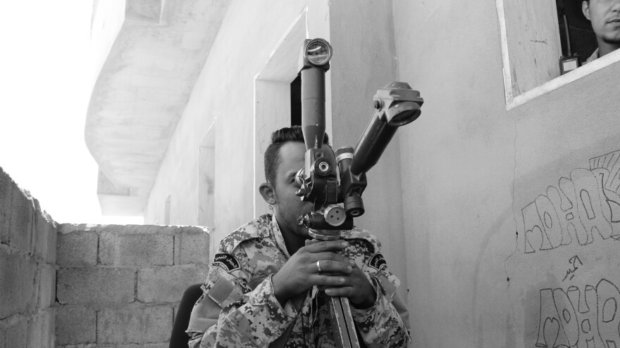 A Libyan soldier peers across the frontline in Sirte during battle against the Islamic State in 2016.