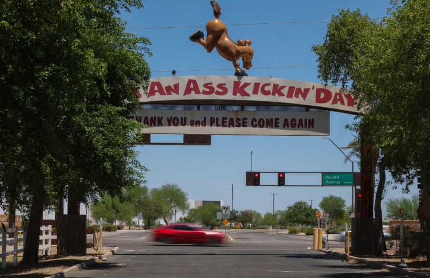 An arch reads Have an ass kickin' day Thank you and please come again over road