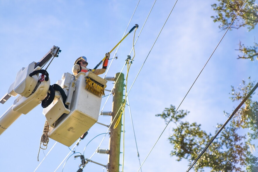 An power company lineman in a bucket truck works the line. 