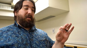 Karl Cronberger holds a slide with a thin section of moon rock on it in a lab at the University of Notre Dame.
