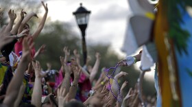 FILE - In this March 2, 2014 file photo, parade-goers cheer for beads and trinkets from float riders as the Krewe of Bacchus Mardi Gras parade rolls down Napoleon Ave. in New Orleans. A spike in violent crime in the French Quarter is unsettling residents and comes just as New Orleans prepares to host crowds of tourists for Mardi Gras.