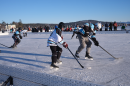 Players battle for a puck on the ice at the 17th annual New England Pond Hockey Classic