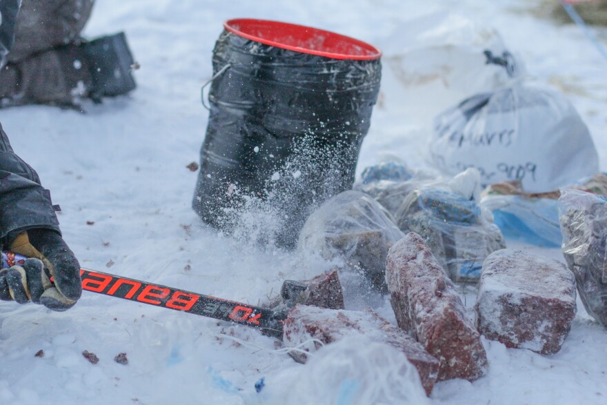An axe slams into some frozen blocks of meat