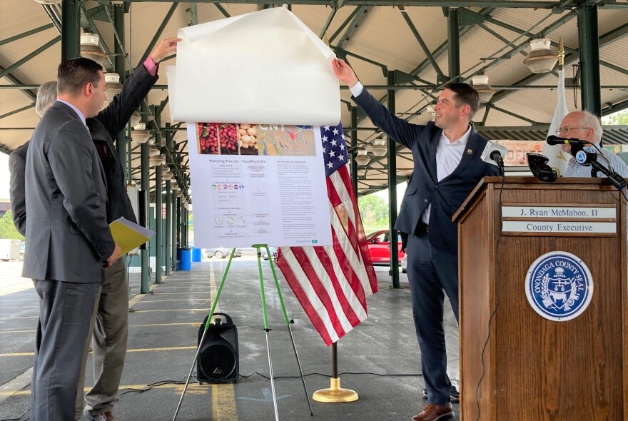 Onondaga County Legislature Chairman Dave Knapp (behind County Executive Ryan McMahon) and Syracuse Mayor Ben Walsh unveil FoodPlan CNY as SUNY ESF Professor and principal author Matthew Potteiger looks on behind the podium.