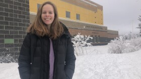 A girl stands for a photo in winter in front of her high school building