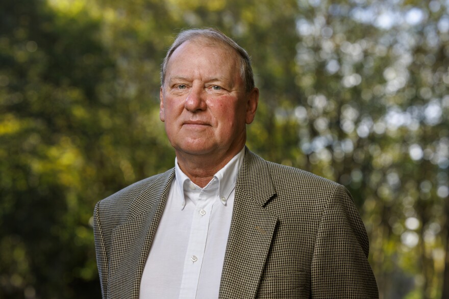 Man in a brown sportcoat and white shirt looking into the camera