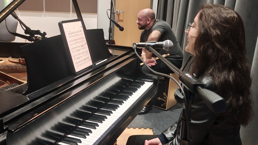 A pianist and percussionist perform in a Jefferson Public Radio studio, seated at a grand piano with sheet music and microphones during a live session.