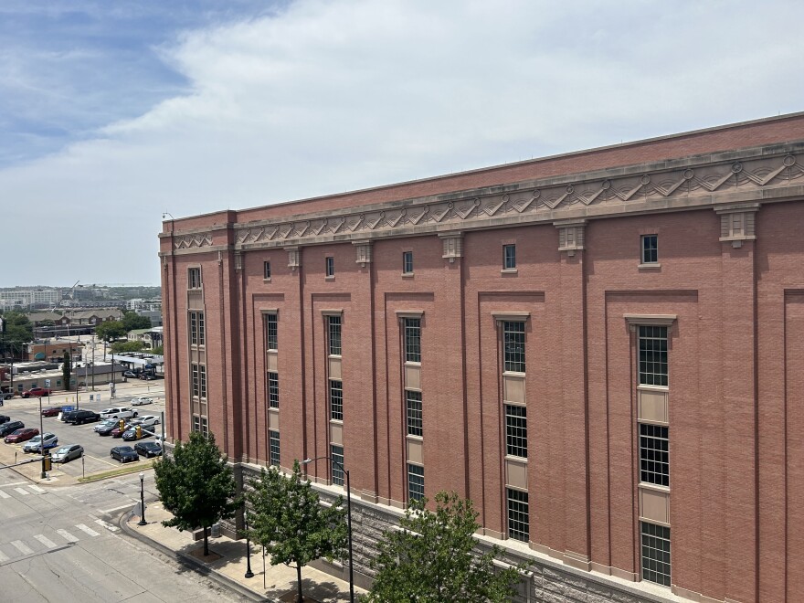  A big, red brick jail that takes up a full city block. The windows are dark, and art deco stonework lines the top. It doesn't look like it would be a jail. There's a parking lot and buildings in the distance.