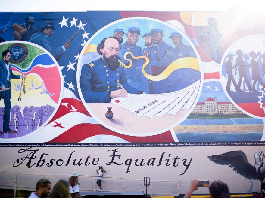 People take pictures next to a mural during a Juneteenth celebration in Galveston, Texas, on June 19, 2021. Last year, the U.S. designated Juneteenth a federal holiday with President Joe Biden urging Americans "to learn from our history."