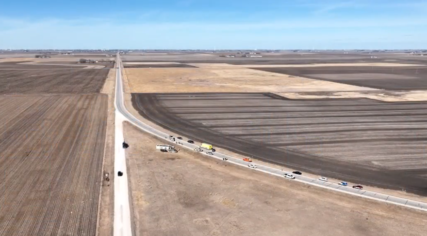 Wide shot from the sky of an accident scene shows a curve with several police cars ambulances.