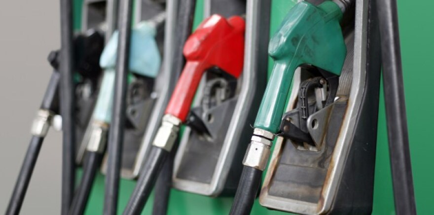 A photo showing four gas pump handles of different colors with hoses attached.