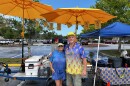 Man and woman stand in front of mobile hot dog cart setup. 
