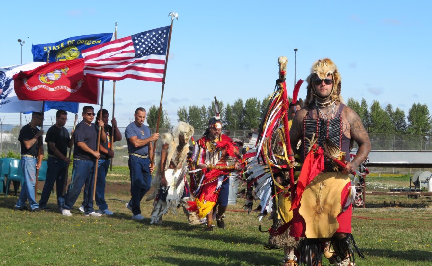 Men at powwow, dancing or holding flags. 