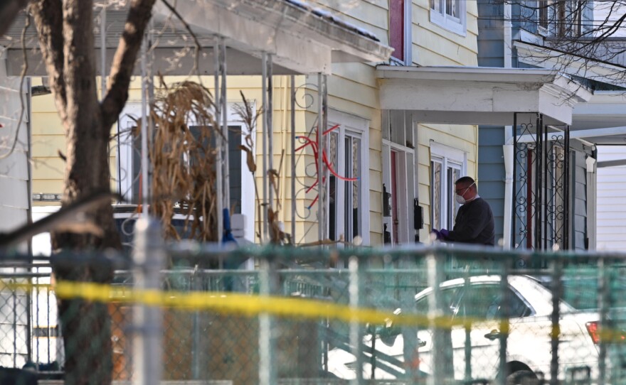 A masked investigator is seen on the porch of a New Alexander Street in Wilkes-Barre Tuesday afternoon, Feb. 24, 2026.