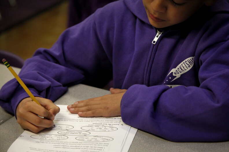 A student writes on worksheets in class.