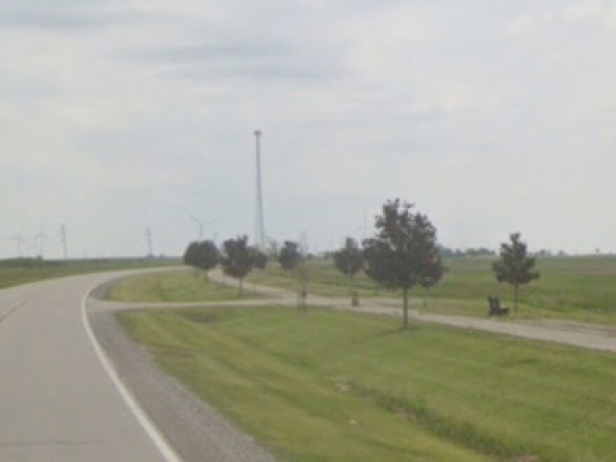 image of a hiking biking trail next to a rural road, with young trees along the side of the trail.