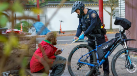 FILE - Portland police central bike squad Officer Joey Yoo issues a citation for drug possession in the city’s Old Town neighborhood in downtown Portland, Ore., Nov. 15, 2023.