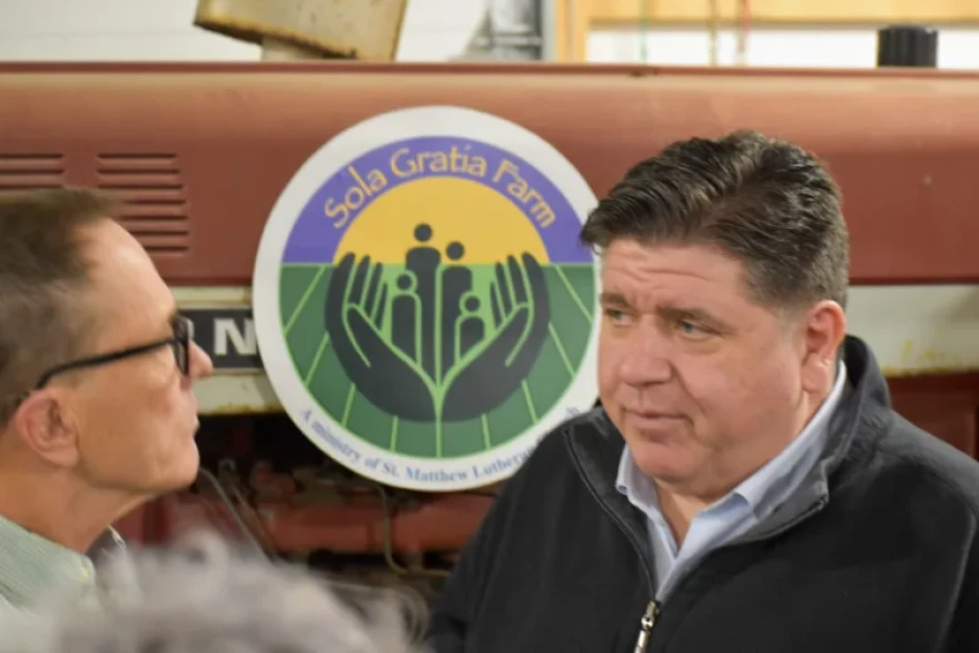 Illinois Gov. JB Pritzker talks with volunteer Tod Satterthwaite at Sola Gratia Farm in Urbana, Illinois on March 19, 2025. Farmers and environmental leaders who saw agriculture funding cuts were also in attendance.