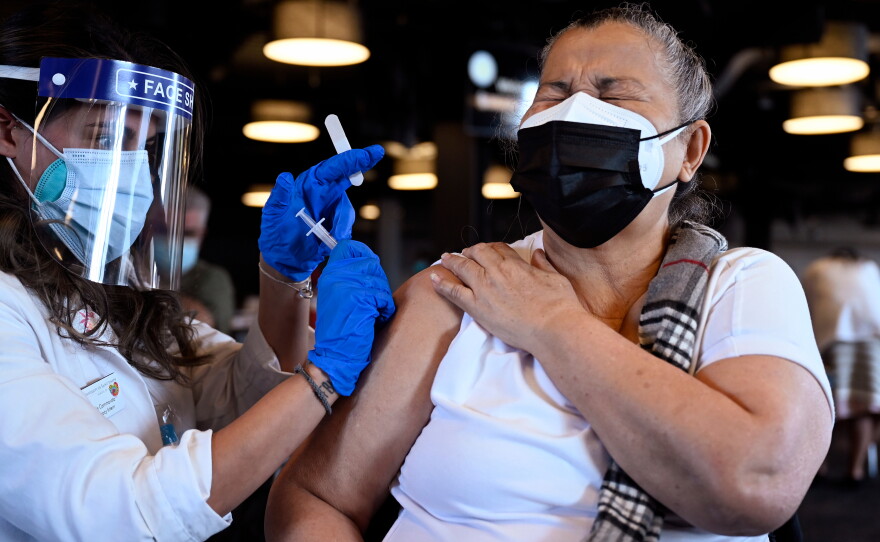 Juanita Sierra, 70, reacts as she gets her first shot of the COVID-19 vaccine from Nicole Cammarota, a University of Saint Joseph pharmacy intern, during the city of Hartford’s Department of Health and Human Services clinic for older Hartford residents at Dunkin’ Donuts Park on Feb. 6, 2021.