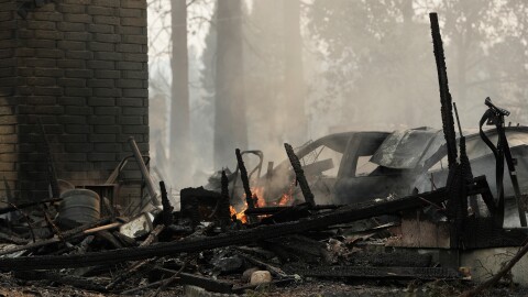 A house on N. Victor St. and W. Lyons Ave. burned by a wildfire smolders, Sunday, Aug. 2, 2026, in Spokane, Wash. 