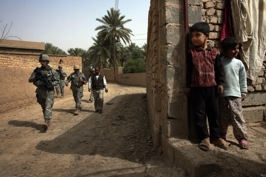 March 19, 2008: An Iraqi boy watches as U.S. soldiers patrol through his neighborhood in Diyala province, northeast of Baghdad.