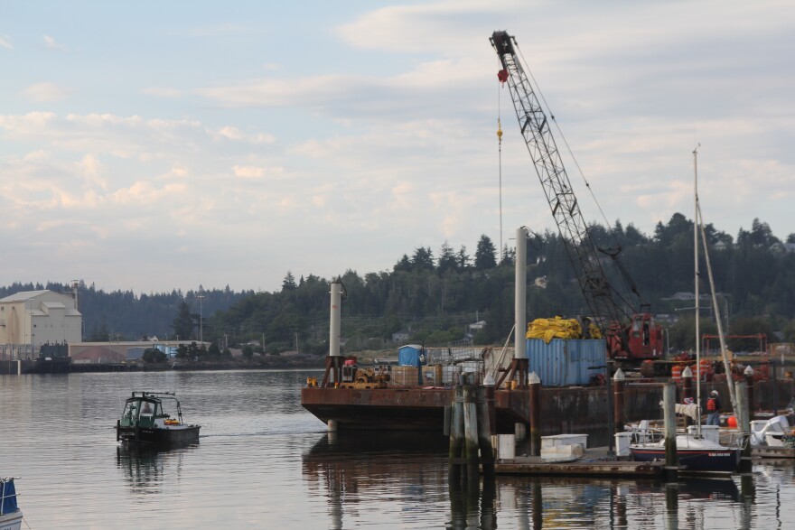 A crane sits on a barge in the bay. Local marine salvage and construction company Billeter Marine began the emergency operation Wednesday morning a the City Marina in Coos Bay.
