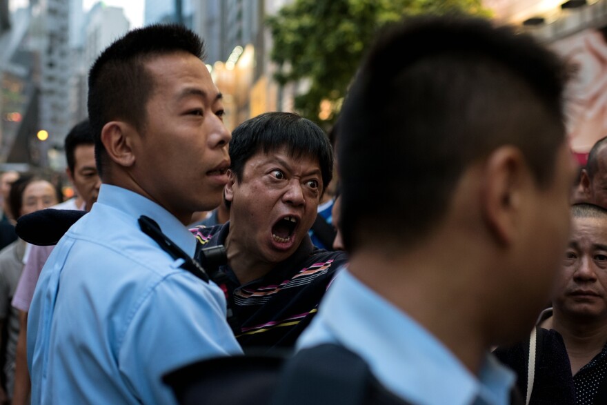 A man is held back by police as he screams at pro-democracy protesters to stop occupying an area of the Causeway Bay district.