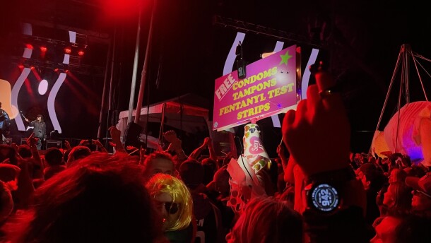 A nighttime shot of a Treefort Music Fest concert with the Festival Fairy sign sticking above the crowd. The picture is bathed in red from the stage lighting. 