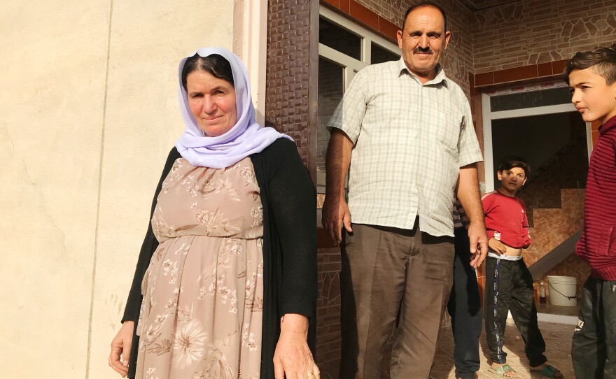 Nofa Khudeda (left) and her husband Ali Edo with neighborhood children just minutes after the couple arrived home in their village of Tel Qasab after six years in a camp for displaced Yazidis.