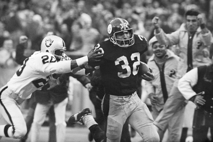 FILE - Pittsburgh Steelers' Franco Harris (32) eludes a tackle by Oakland Raiders' Jimmy Warren as he runs 42-yards for a touchdown after catching a deflected pass during an AFC Divisional NFL football playoff game in Pittsburgh, Dec. 23, 1972. Harris' scoop of a deflected pass and subsequent run for the winning touchdown — forever known as the "Immaculate Reception" — has been voted the greatest play in NFL history. On the 50th anniversary of the "Immaculate Reception" — Friday, Dec. 23, 2022 — Pittsburghers recall how it boosted morale during the collapse of the steel industry and has served as a cultural rallying point ever since.