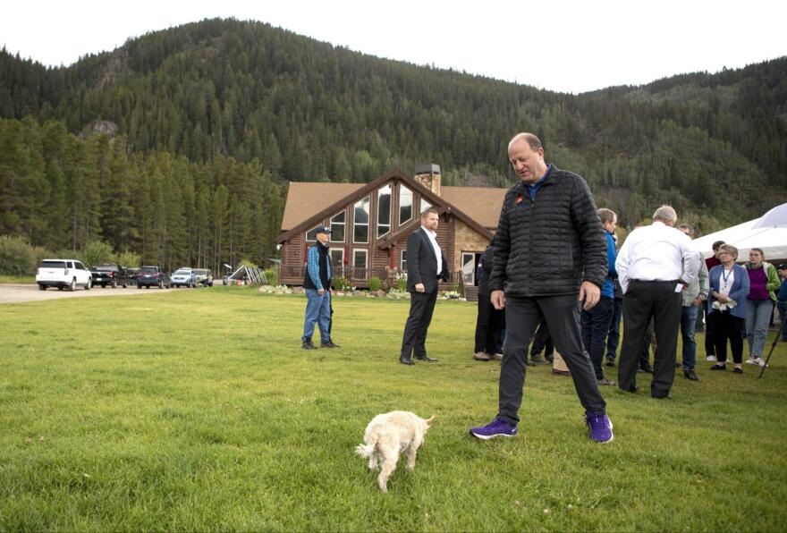 Colorado Gov. Jared Polis walks to pick up his dog, Gia, during a visit at Camp Hale on Tuesday, Aug. 16, 2022, near Leadville.