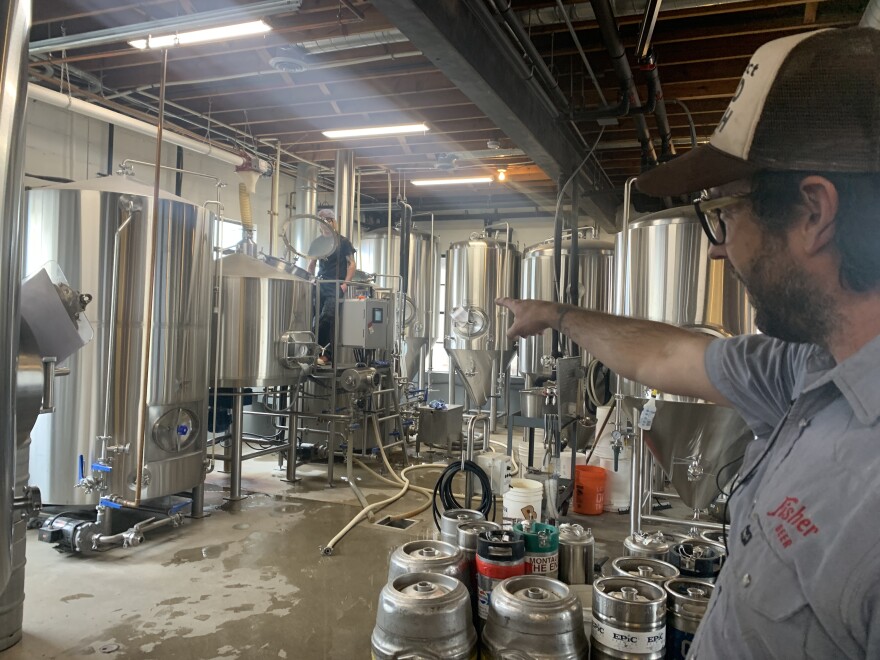 Man pointing at beer brewing equipment.