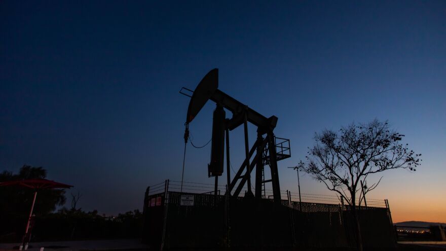 An oil pumpjack operates at dusk Willow Springs Park in Long Beach, Calif. Producers have kept pumping, even if they're not making money, partly because wells — once shut down — can be difficult to get back up and running. [Apu Gomes / AFP via Getty Images]