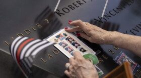 A person puts photos of fallen firefighters on the 9/11 Memorial during the commemoration ceremony on the 22nd anniversary of the September 11, 2001, terror attacks on Monday, Sept. 11, 2023, in New York. (AP Photo/Yuki Iwamura)