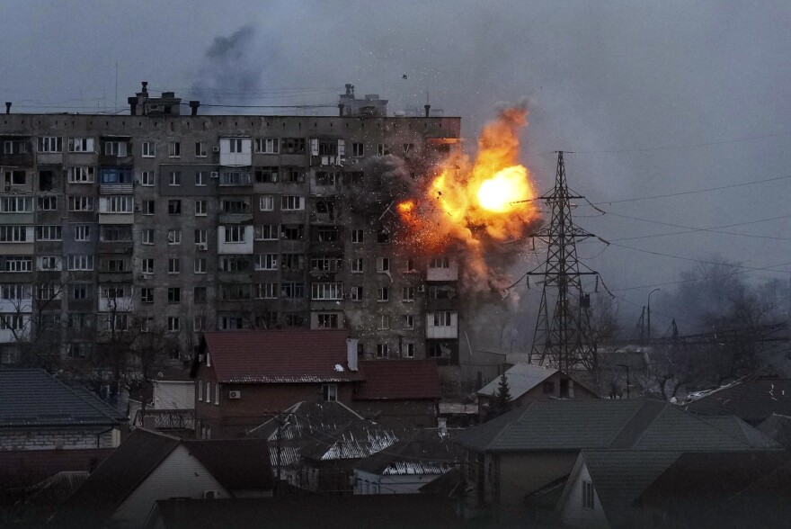 An explosion is seen in an apartment building after a Russian army tank fires in Mariupol, Ukraine, on Friday.