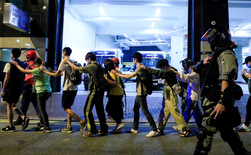 Protesters are escorted by police out of the campus of Hong Kong Polytechnic University during clashes with police in Hong Kong on Monday.